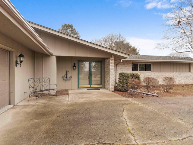 doorway to property with a garage and brick siding