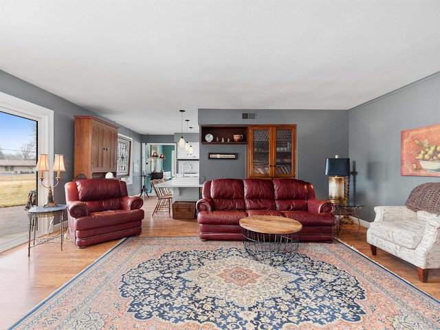 living area featuring light wood-style flooring, visible vents, and baseboards