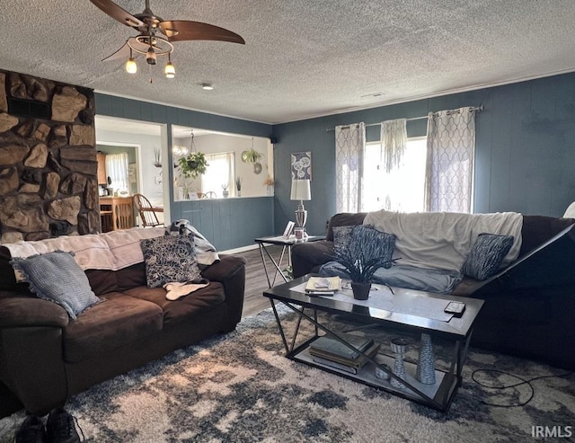 living room featuring crown molding, a textured ceiling, a ceiling fan, and wood finished floors