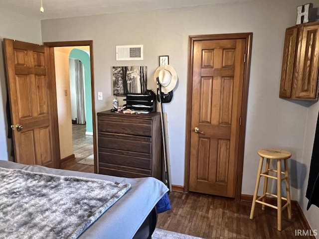 bedroom with arched walkways, dark wood-style flooring, visible vents, and baseboards