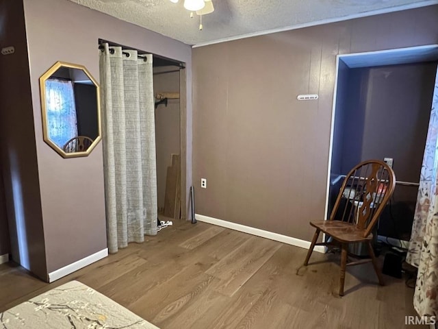 bedroom featuring a textured ceiling, baseboards, and wood finished floors