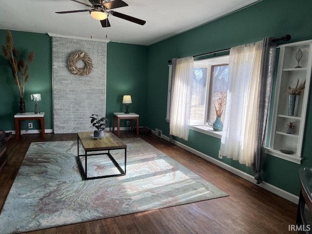 living area with a ceiling fan, wood finished floors, visible vents, and baseboards