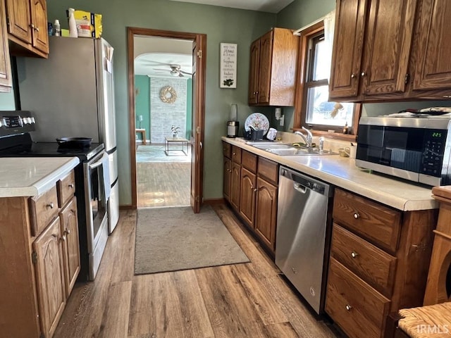 kitchen featuring appliances with stainless steel finishes, light wood-style floors, light countertops, and a sink