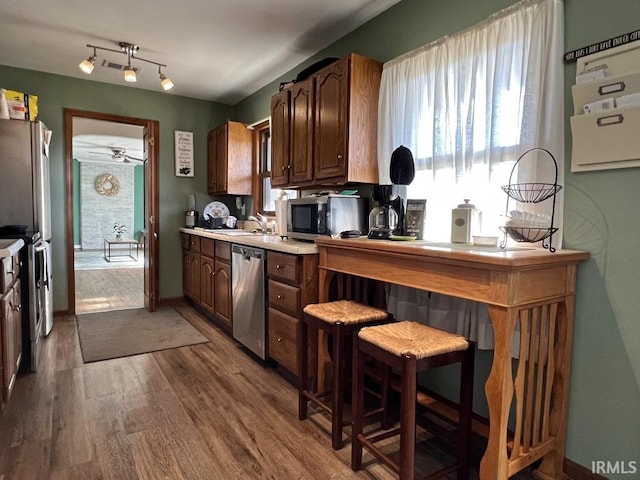 kitchen featuring ceiling fan, stainless steel appliances, wood finished floors, a sink, and light countertops