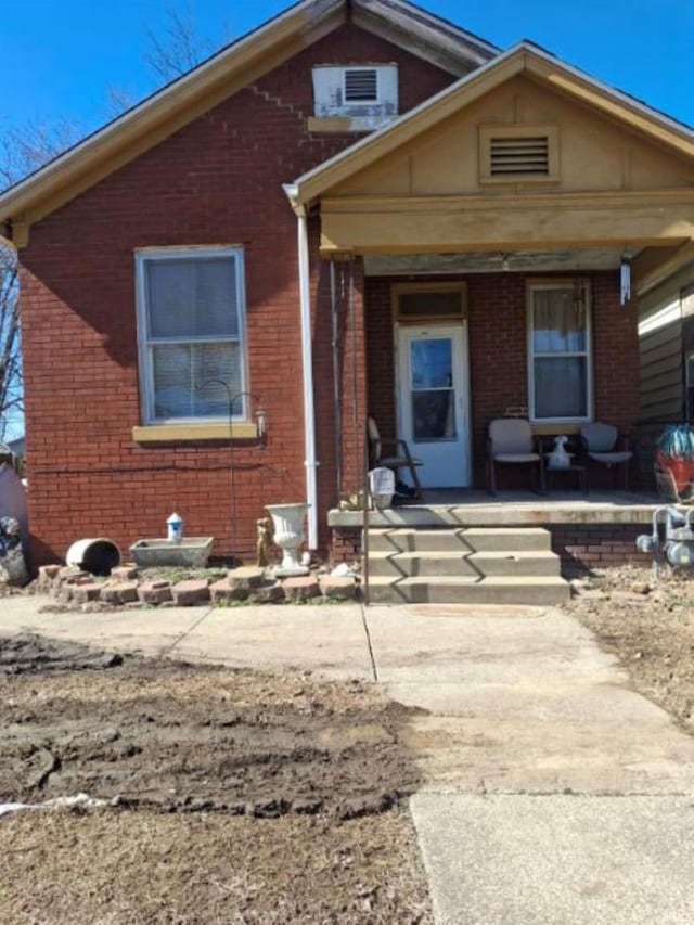 bungalow with covered porch and brick siding