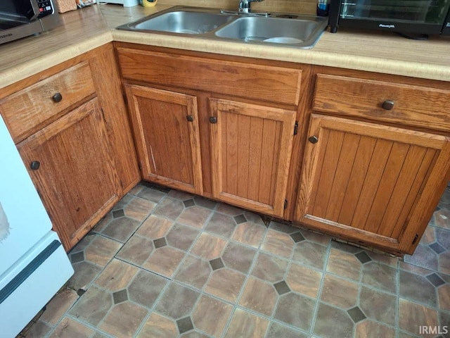 kitchen featuring brown cabinetry, light countertops, and a sink