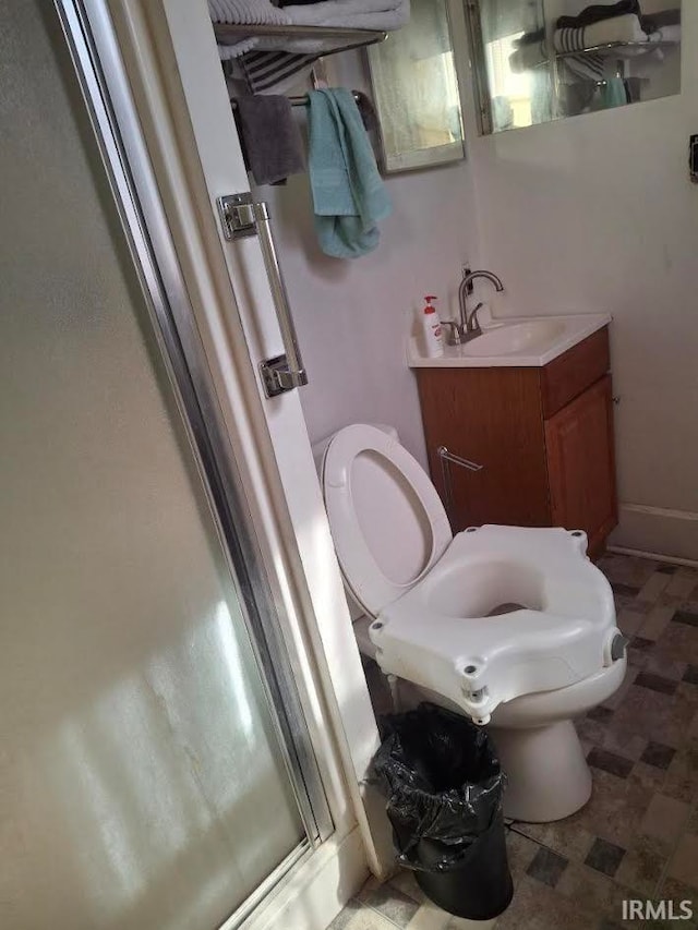 bathroom with a stall shower, vanity, toilet, and baseboards