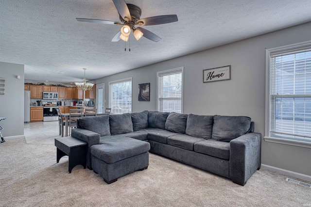 living room with ceiling fan with notable chandelier, baseboards, visible vents, and light colored carpet