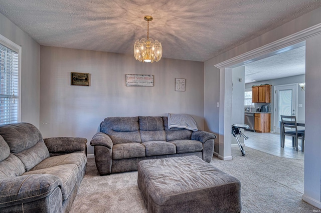 living room with an inviting chandelier, baseboards, a textured ceiling, and light colored carpet