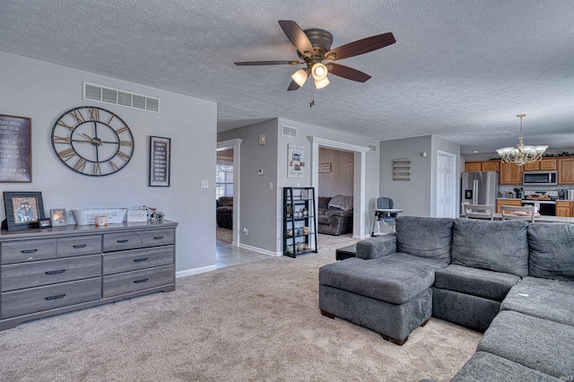 living room featuring a textured ceiling, light carpet, ceiling fan with notable chandelier, visible vents, and baseboards