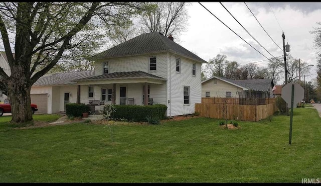 view of front of house with an attached garage, fence, and a front lawn