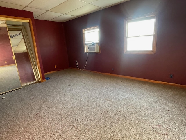 empty room featuring baseboards, cooling unit, a drop ceiling, and carpet flooring