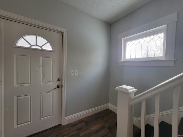 entrance foyer featuring dark wood-style floors, baseboards, and a textured ceiling