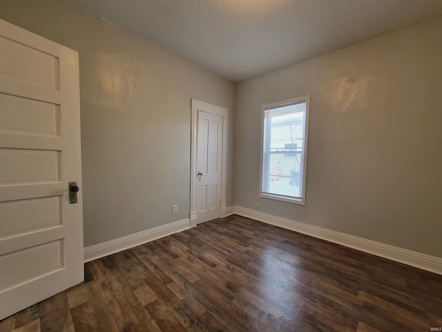 unfurnished room featuring dark wood-style flooring and baseboards