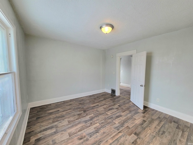 spare room featuring a textured ceiling, wood finished floors, and baseboards