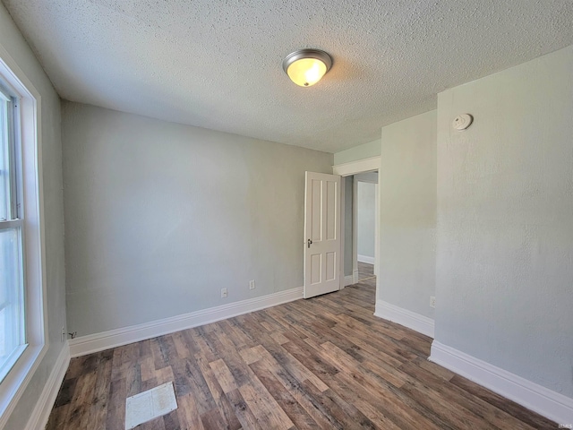 unfurnished room featuring a textured ceiling, baseboards, and wood finished floors