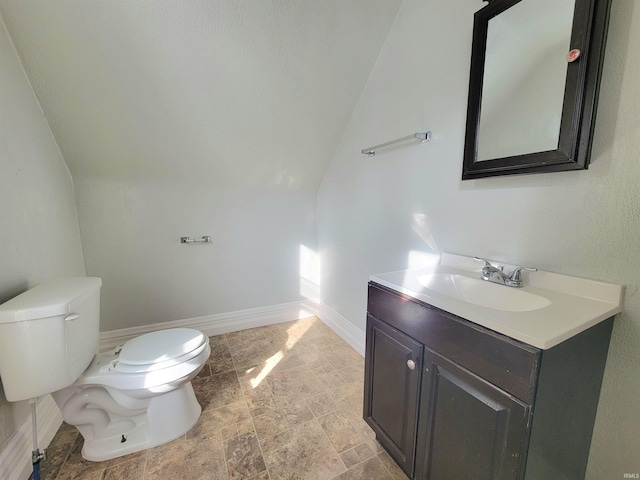 bathroom featuring baseboards, vaulted ceiling, vanity, and toilet