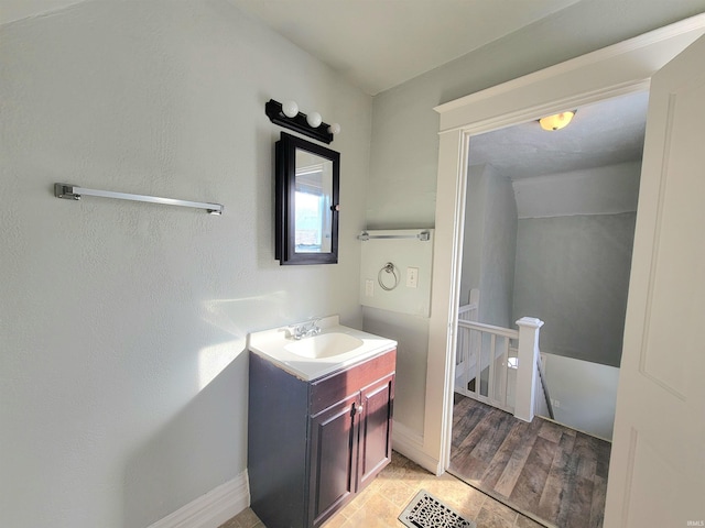 bathroom featuring visible vents, wood finished floors, vanity, and baseboards