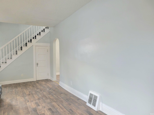 spare room with baseboards, visible vents, arched walkways, stairway, and wood finished floors