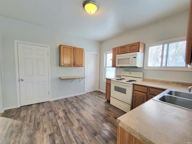 kitchen with white appliances, a sink, baseboards, brown cabinets, and dark wood finished floors