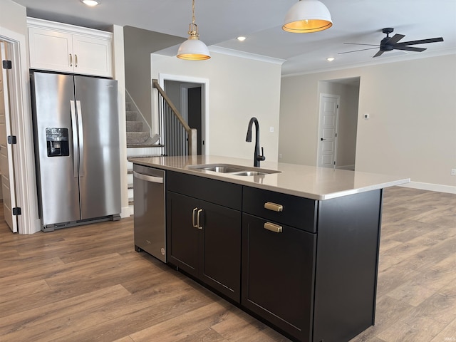 kitchen with stainless steel appliances, light wood-style floors, decorative light fixtures, and a sink