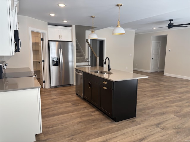 kitchen featuring wood finished floors, appliances with stainless steel finishes, a sink, and white cabinetry