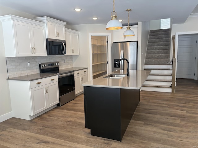 kitchen with a sink, appliances with stainless steel finishes, tasteful backsplash, dark wood finished floors, and pendant lighting