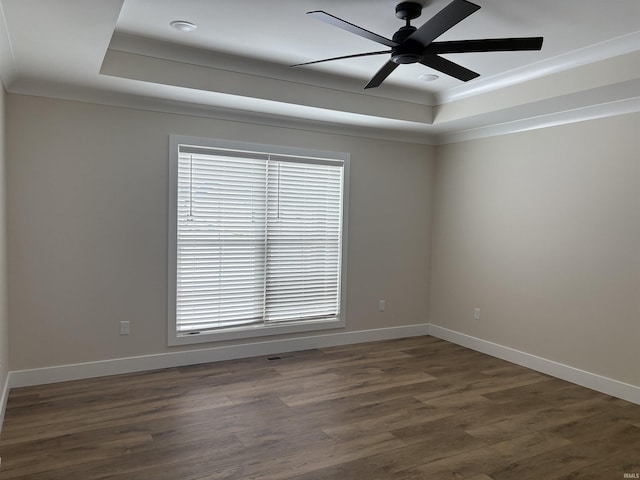 unfurnished room featuring wood finished floors, a raised ceiling, and baseboards