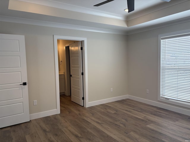 spare room with baseboards, ceiling fan, ornamental molding, wood finished floors, and a tray ceiling