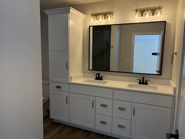 full bath featuring double vanity, a sink, toilet, and wood finished floors