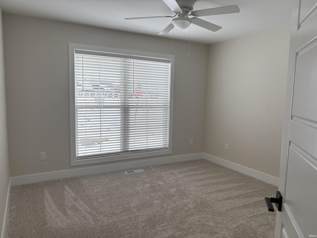 carpeted empty room featuring visible vents, ceiling fan, and baseboards