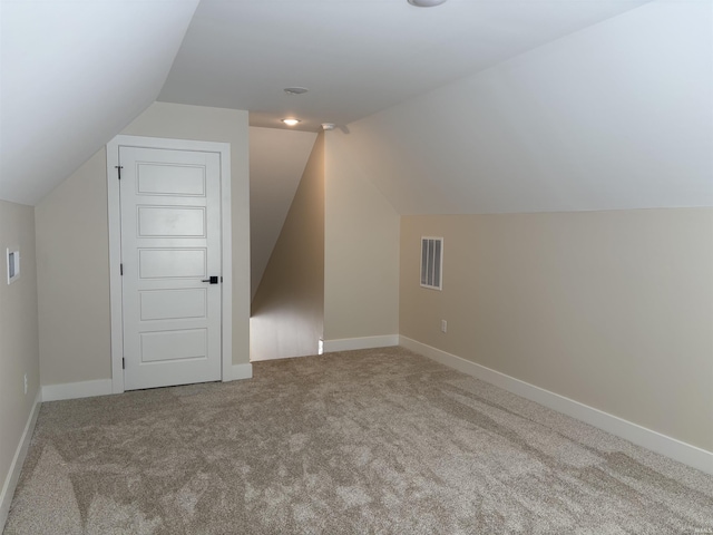 additional living space with baseboards, visible vents, vaulted ceiling, and carpet flooring