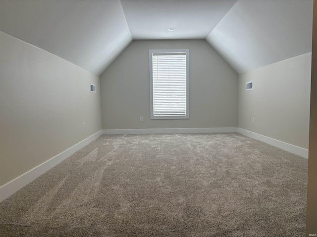 bonus room featuring lofted ceiling, baseboards, light carpet, and visible vents