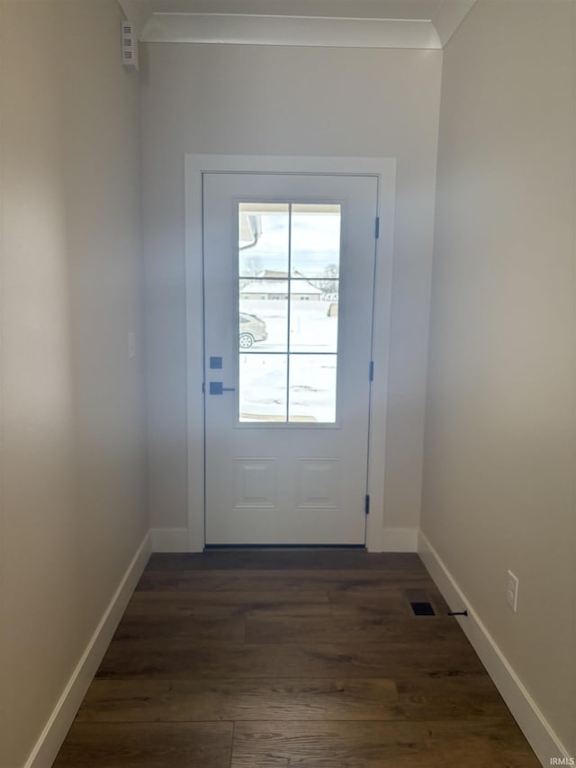 doorway with visible vents, baseboards, dark wood finished floors, and crown molding