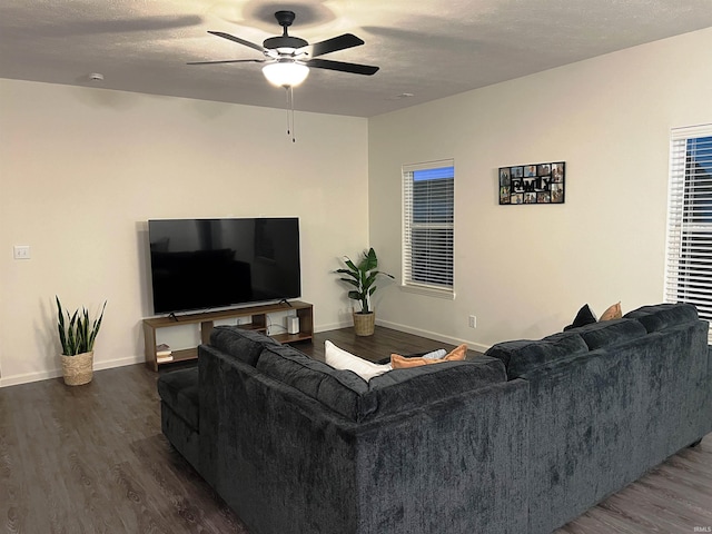 living area featuring dark wood-style floors, a textured ceiling, baseboards, and a ceiling fan