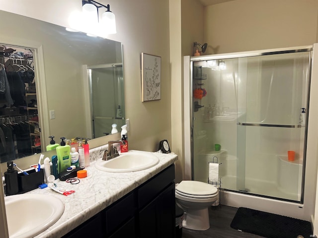 full bath featuring a stall shower, a sink, toilet, and double vanity