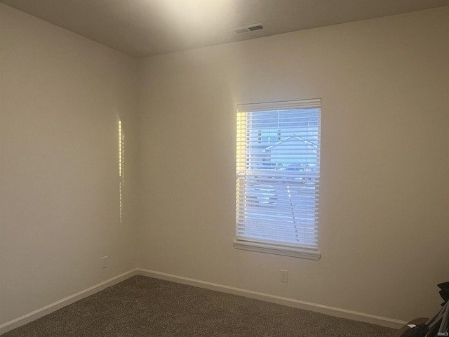 unfurnished room featuring dark colored carpet, visible vents, and baseboards