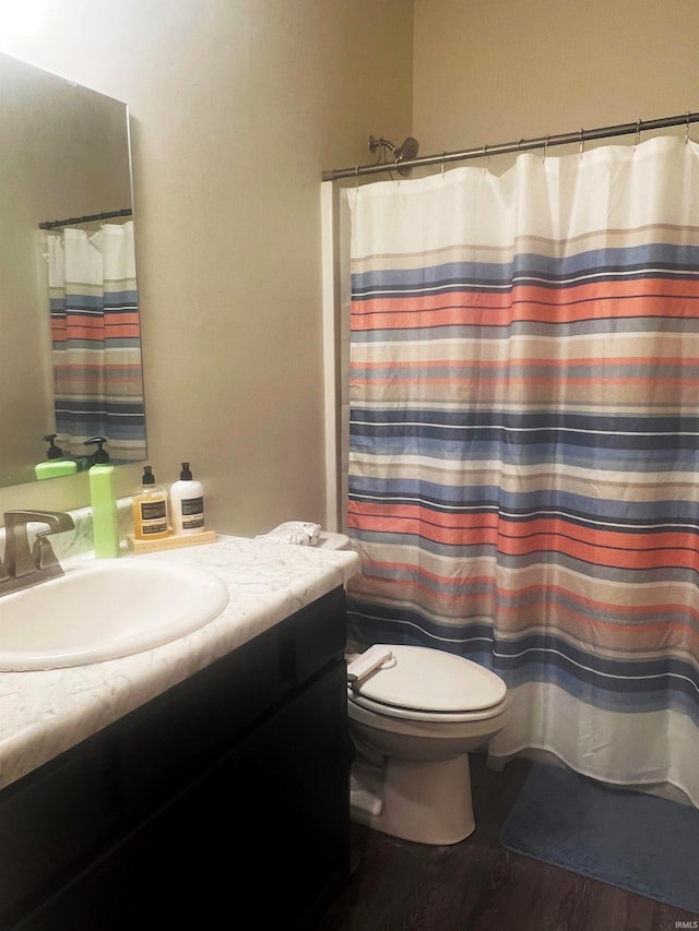 bathroom with toilet, curtained shower, wood finished floors, and vanity