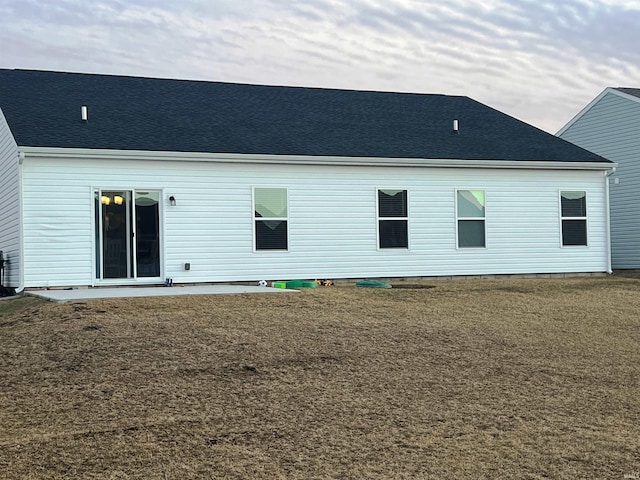 rear view of property with a yard and a shingled roof