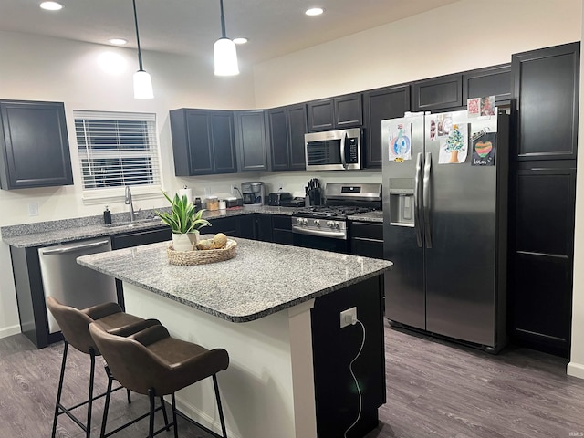 kitchen featuring wood finished floors, appliances with stainless steel finishes, a kitchen bar, and a center island