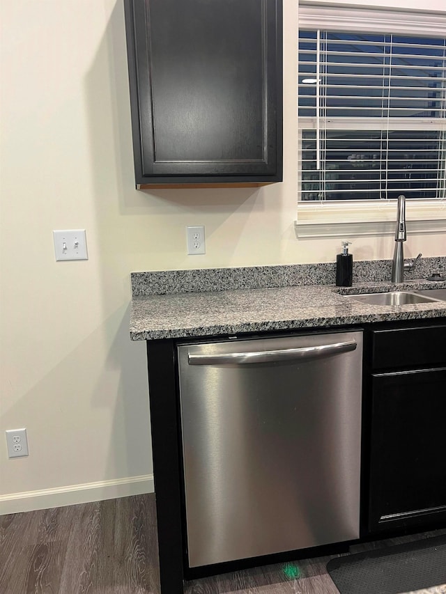 interior details with wood finished floors, stainless steel dishwasher, a sink, and baseboards