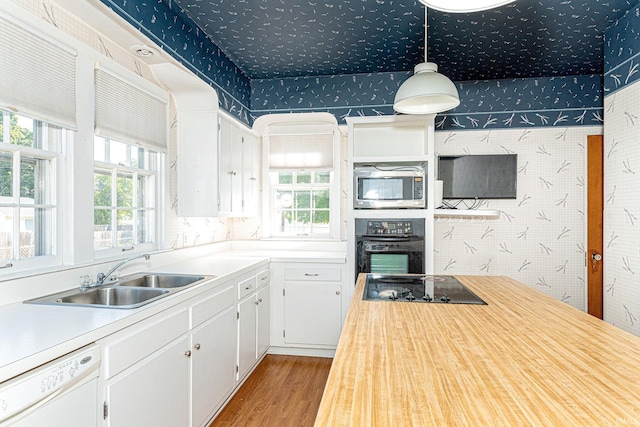 kitchen with black appliances, a sink, light countertops, and wallpapered walls