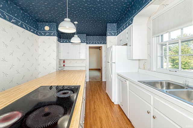 kitchen with black electric stovetop, white dishwasher, white cabinets, and wallpapered walls