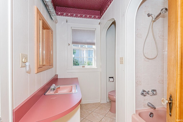 bathroom with baseboards, toilet, tile patterned floors, shower / washtub combination, and a sink