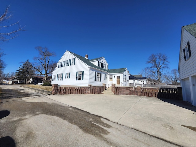 view of home's exterior featuring a chimney, a shingled roof, a deck, a garage, and driveway