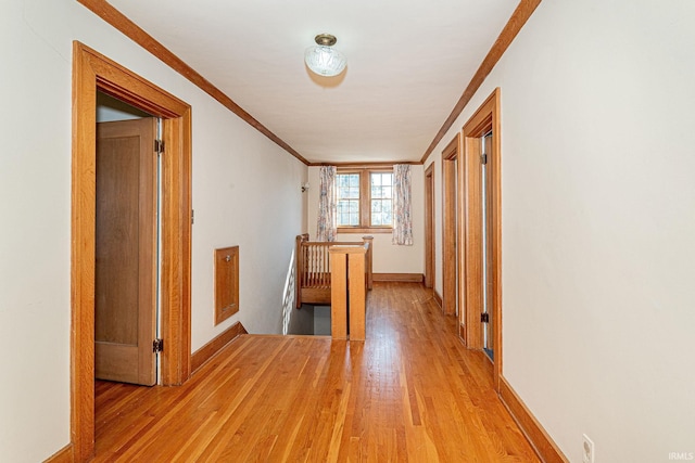 corridor featuring light wood-type flooring, baseboards, crown molding, and an upstairs landing