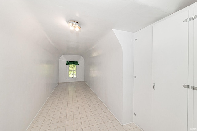 hall featuring lofted ceiling, arched walkways, and light tile patterned flooring