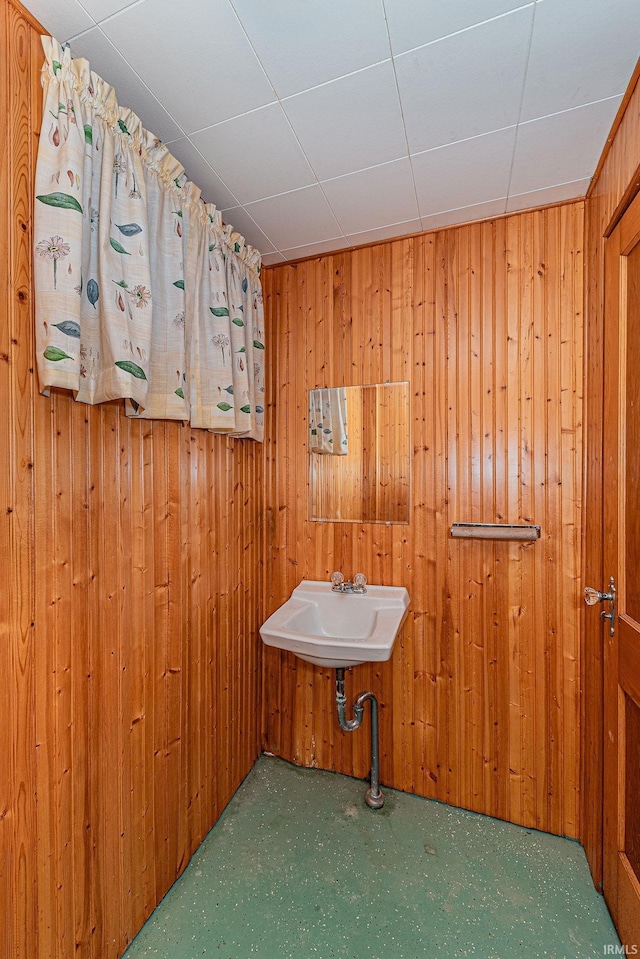 bathroom featuring wooden walls and a sink