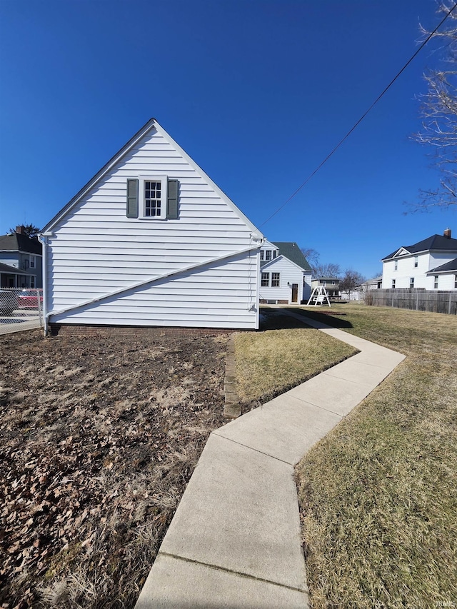 view of side of home featuring a residential view, a yard, and fence