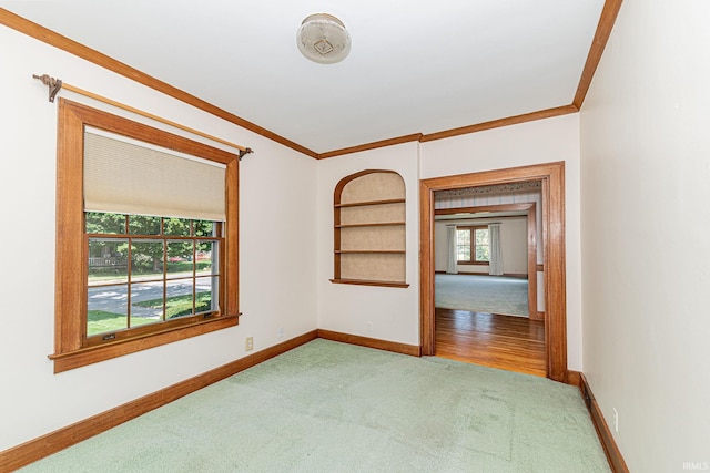 spare room with ornamental molding, built in features, carpet floors, and baseboards